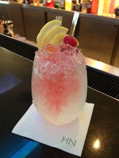 a glass filled with ice and fruit sitting on top of a table next to a bar