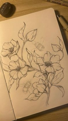 a pencil drawing of flowers on paper next to a pen and ink pad with marker