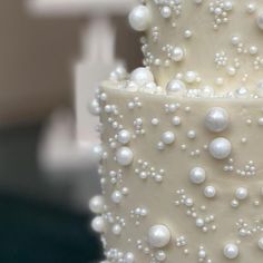 a three tiered white cake with pearls on it