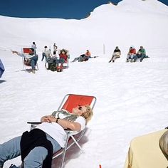 people are lounging in the snow on chairs