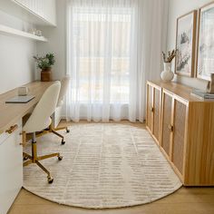 a room with a rug, desk and chair next to a window in the corner