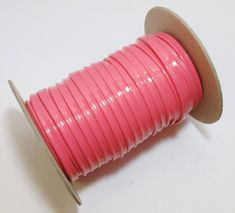 a spool of pink colored cord on a white surface