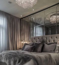 a bedroom with a large bed, chandelier and mirror walls in the corner