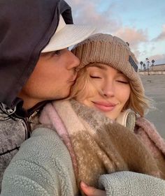 a man and woman kissing each other on the beach