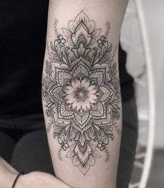 a woman's arm with a tattoo on it that has an intricate flower design