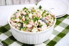 a white bowl filled with salad sitting on top of a green and white checkered table cloth