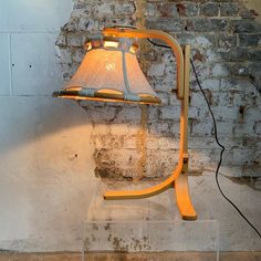 a lamp sitting on top of a glass block next to a brick wall and floor