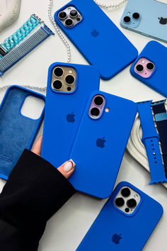 a person holding an iphone case in front of several other cases on a white table