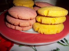 there are three cookies on the plate and one is pink with yellow frosting in it