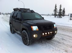 a black truck driving down a snow covered road