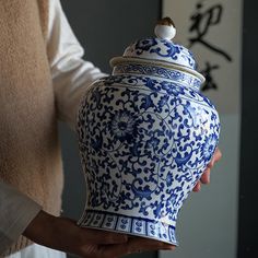 a person holding a blue and white vase in their hand