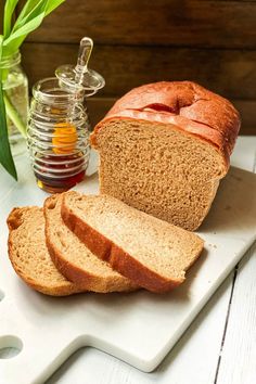 sliced loaf of bread sitting on top of a cutting board next to a jar of honey