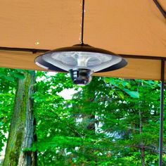 an outdoor area with a table and chairs under a canopy in the woods, surrounded by trees