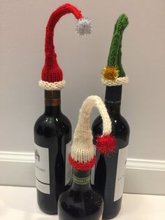 two wine bottles with knitted santa hats on them