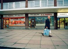 a man is walking down the street with shopping bags in front of storefronts