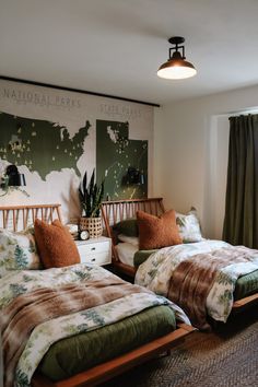 two beds in a room with green curtains and pillows on the bed, next to each other