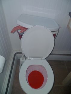 a white toilet with red liquid in it