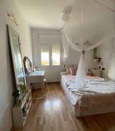 a bedroom with a bed, dresser and mirror in it's corner area that has white drapes hanging from the ceiling