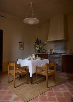 a dining room table with two chairs and a white table cloth on top of it