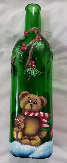 a green glass bottle with a teddy bear holding a candy cane in it's mouth