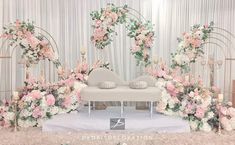 a white couch sitting in front of a flower covered stage with pink and white flowers on it