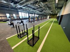 an indoor gym with green grass and white lines on the floor, rows of exercise equipment