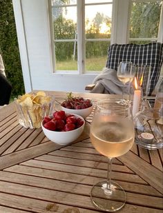 two glasses of wine and some strawberries on a table