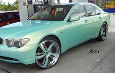 a mint green car parked in front of a gas station