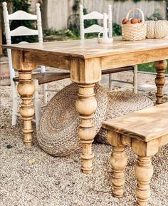 a wooden table sitting on top of a gravel covered ground next to a white chair