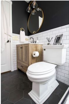 a white toilet sitting in a bathroom next to a wooden cabinet and sink with a mirror above it