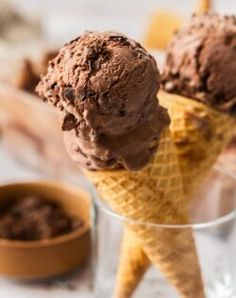 two scoops of chocolate ice cream sitting in a glass on top of a table