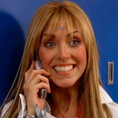 a woman with long blonde hair talking on a cell phone and smiling at the camera