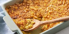 a casserole dish filled with macaroni and cheese topped with a wooden spoon