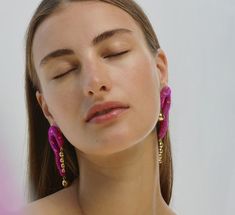 a woman with her eyes closed wearing large pink beaded earring's and looking to the side