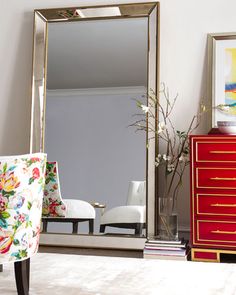 a large mirror sitting on top of a dresser next to a red chest of drawers