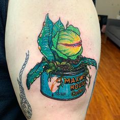 a close up of a person's arm with a tattoo on it and a potted plant