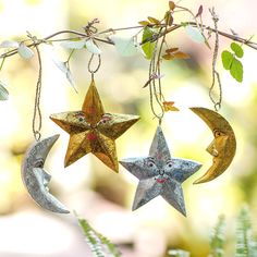 three metal stars hanging from a branch next to a moon and crescent ornament