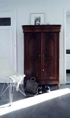 a white chair sitting next to a wooden cabinet