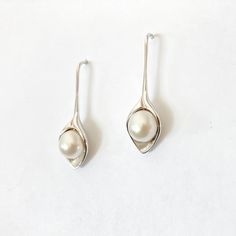 Featuring a classic and sophisticated look, the Lily pearl earrings are a popular choice among customers. These precious pieces are crafted with lustrous freshwater pearls and set in a singularly shaped rhodium setting. Materials: Freshwater pearl. Rhodium setting. Drop Length: 1" Make it a set with our matching Lily necklace. Original copyright design