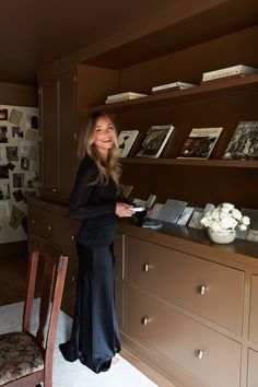 a woman standing in front of a desk with books on it