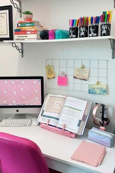 a desk with a computer monitor, keyboard and notebook on it in front of a shelf filled with books