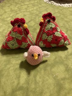 two crocheted birds sitting next to each other on a bed