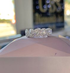 three stone diamond ring sitting on top of a pink display case at a jewelry store