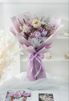 a bouquet of flowers sitting on top of a table next to an open book and vase