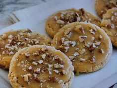 some cookies with nuts on top are sitting on a white plate