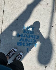 the shadow of a person standing next to a sidewalk with graffiti on it that reads me, map and soft