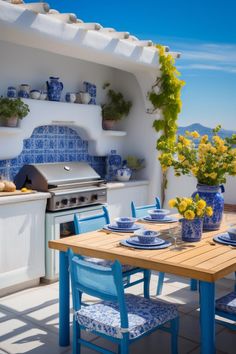 an outdoor dining area with blue and white dishes on the table, yellow flowers in vases