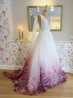 a wedding dress on display in front of a mirror with flowers and leaves all over it