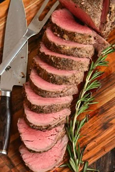 sliced roast beef on cutting board with knife and rosemary sprig