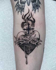 a black and white tattoo on the leg of a person with a cross, skull and wings